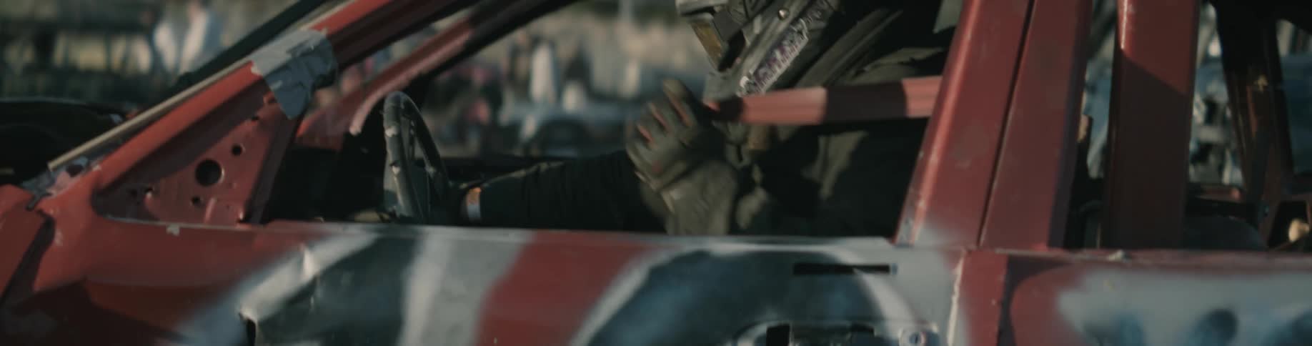A person is sitting in a parked car and wearing a helmet