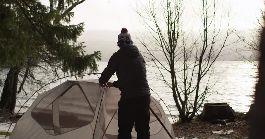 A man is finishing up setting up a tent