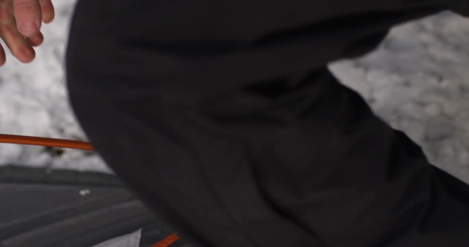 A person is assembling a tent on snow