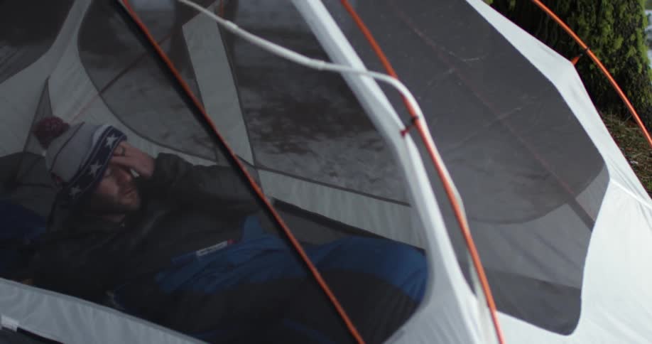 Man emerges from a sleeping bag while laying in a tent