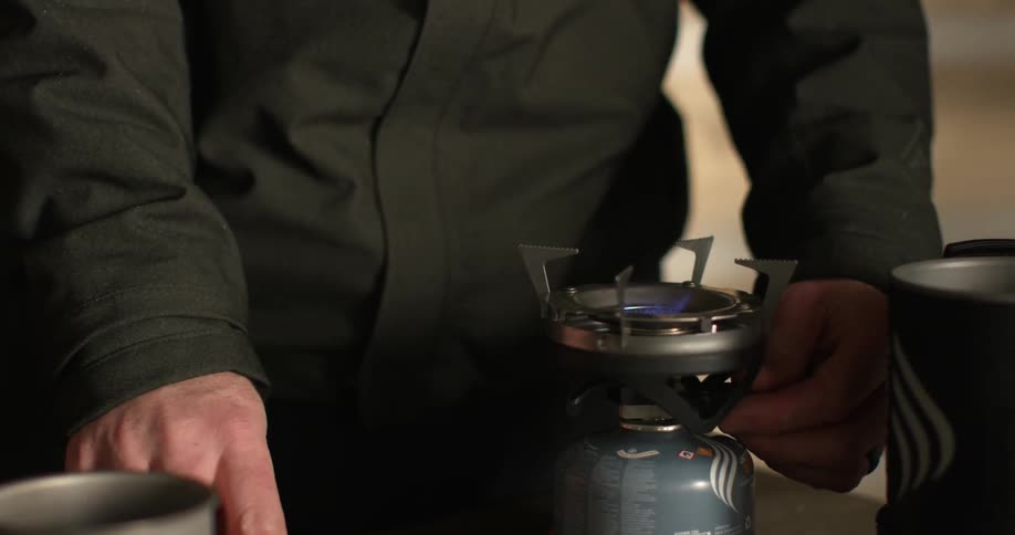 A man lights a small torch and puts a thermos on it to heat