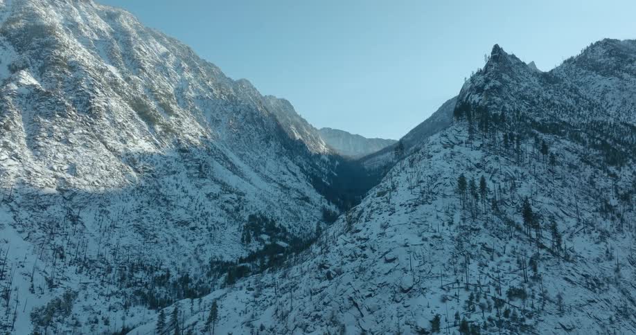 Peeking into a cold and deep canyon between two snowy peaks
