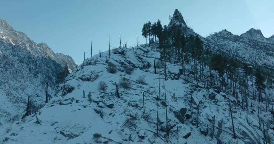 Dynamic orbit around a steep mountain ridge to reveal a deep and dark valley below