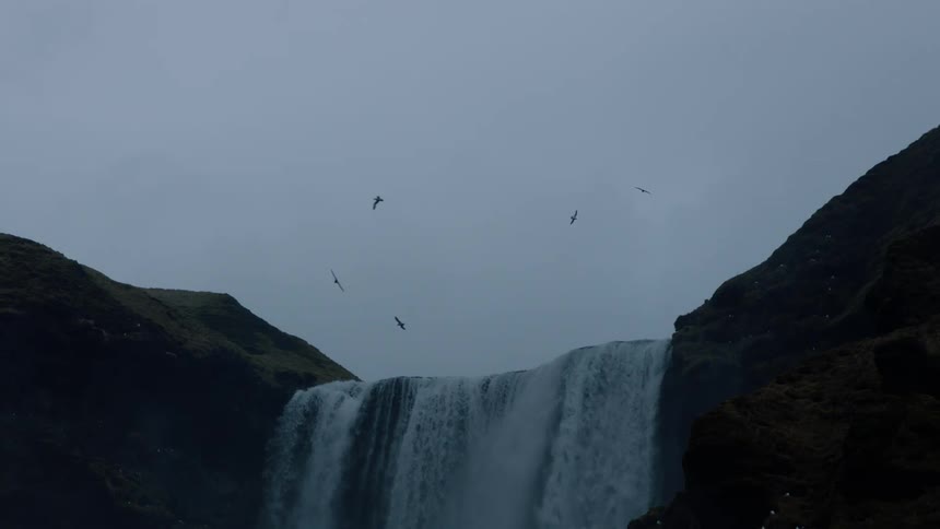 A view of birds flying around above a waterfall