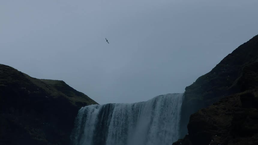 High waterfall cascading down on cloudy day