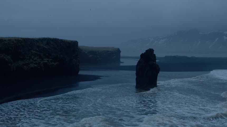 Waves rolls over the beach near steep cliffs