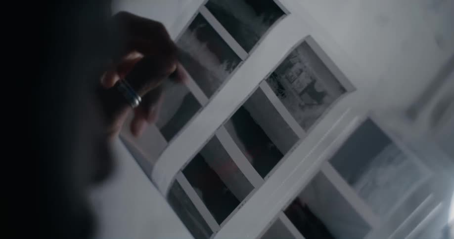 A person is holding photo negatives in the dark room