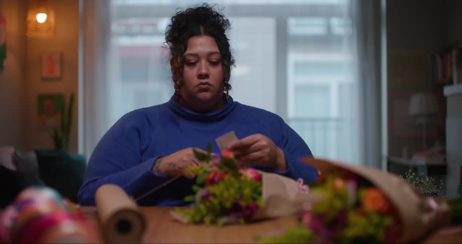 A woman florist is putting a card in a bouquet of flowers