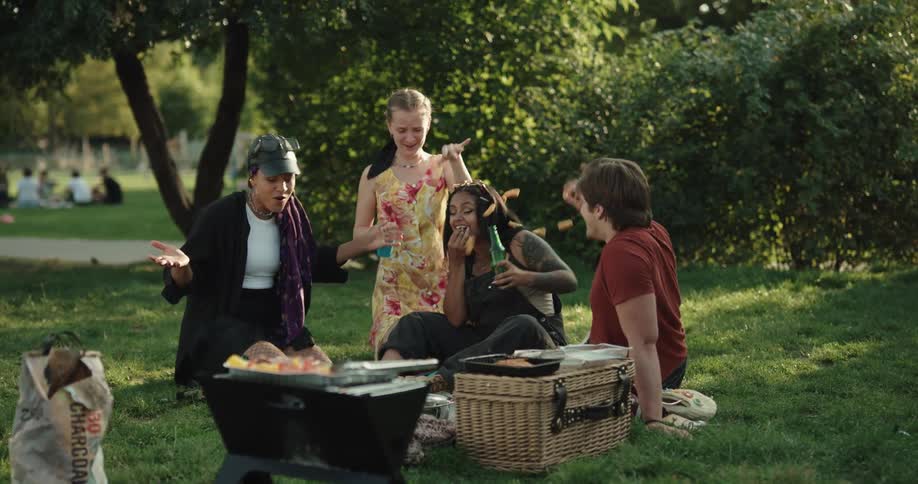 Friends grilling in park during picnic have a food fight