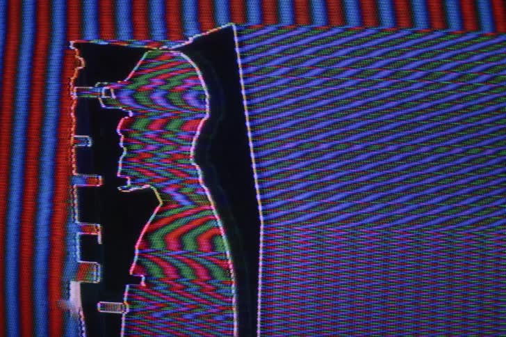 The image of a man in profile on a digital screen distorts and pixelates