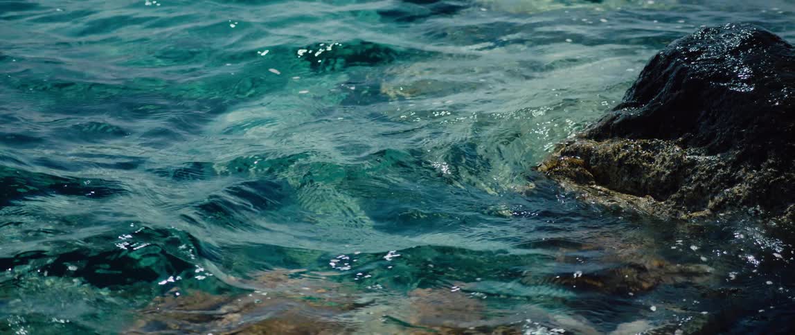 Ocean waves wash over large rocks in the sea