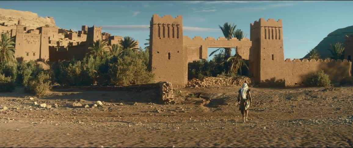 A man walks across soil towards a castle