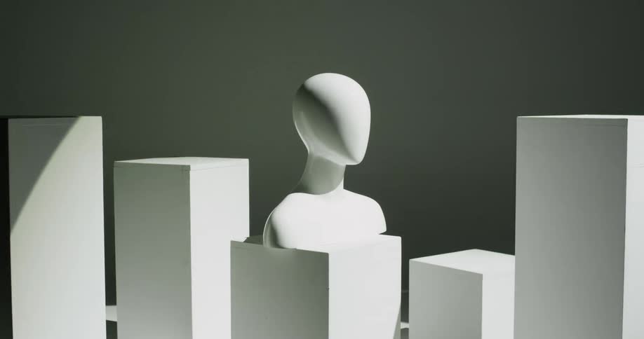 A bright light washes over a room where a human bust sits on a short pedestal