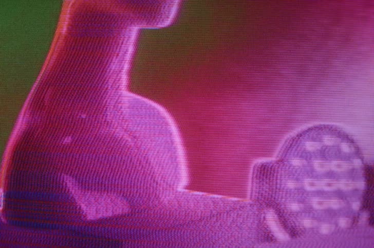A screen repeatedly flashes and changes color as a human bust and a shower head are on display