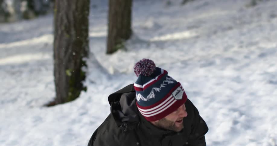 Man smiles while throwing a snowball outside