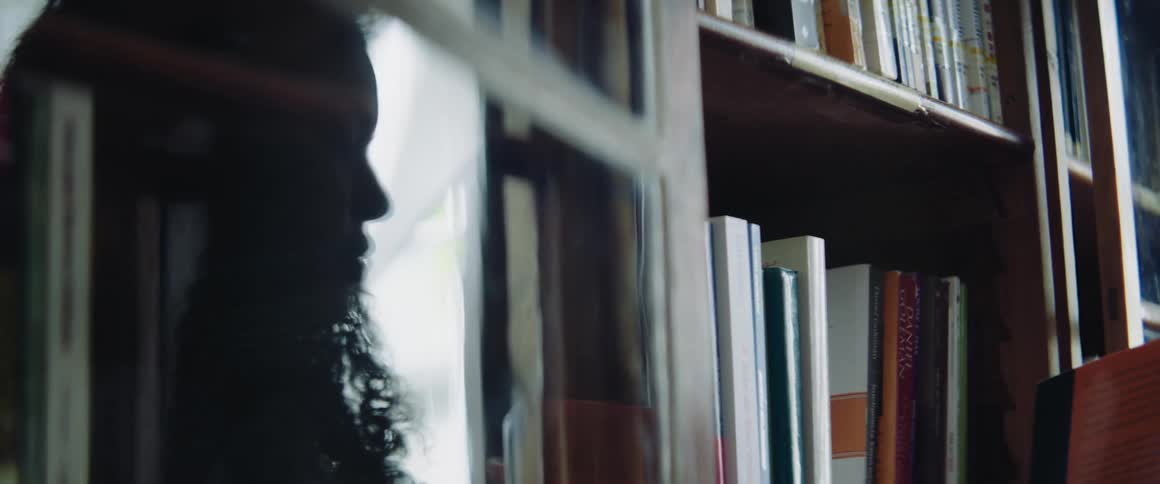 A teenager takes a book of of a library shelf