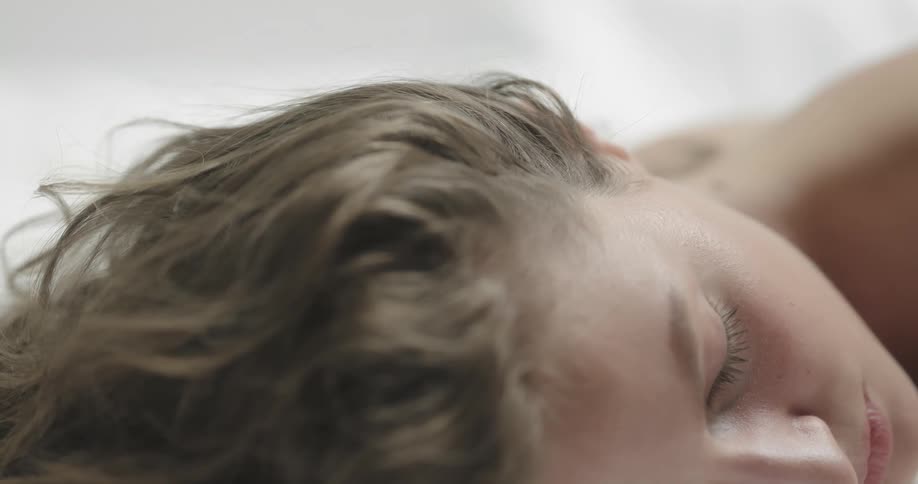 A woman sleeps face down on crisp white sheets