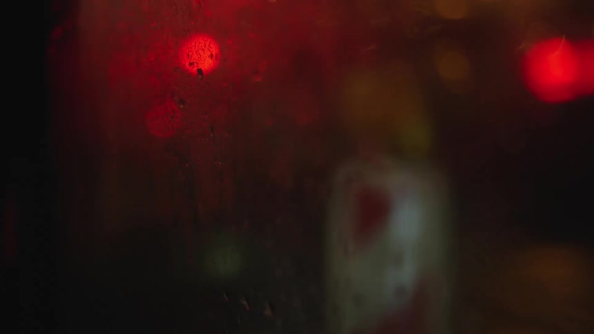 Rain on a car window with lights shining outside