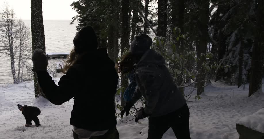 A group of people engage in a snowball fight in a forested area