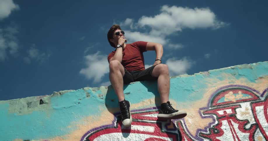 A man sits on the wall smoking
