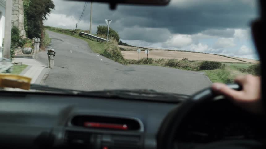 A person in a car driving up a narrow road