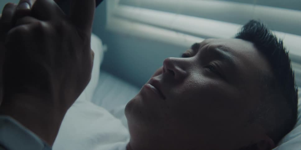 A man checks his smartphone while trying to sleep