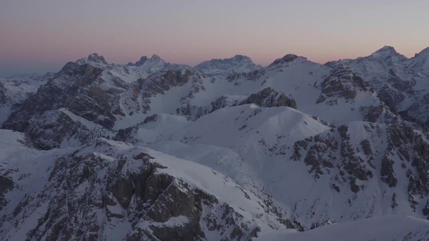 Snow covered mountains stretch to the horizon under a red sky