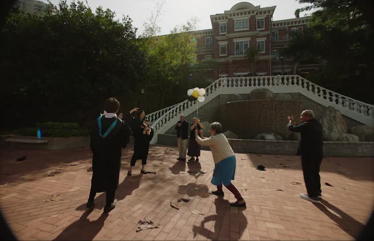 Graduates pose for pictures near a large brick school building