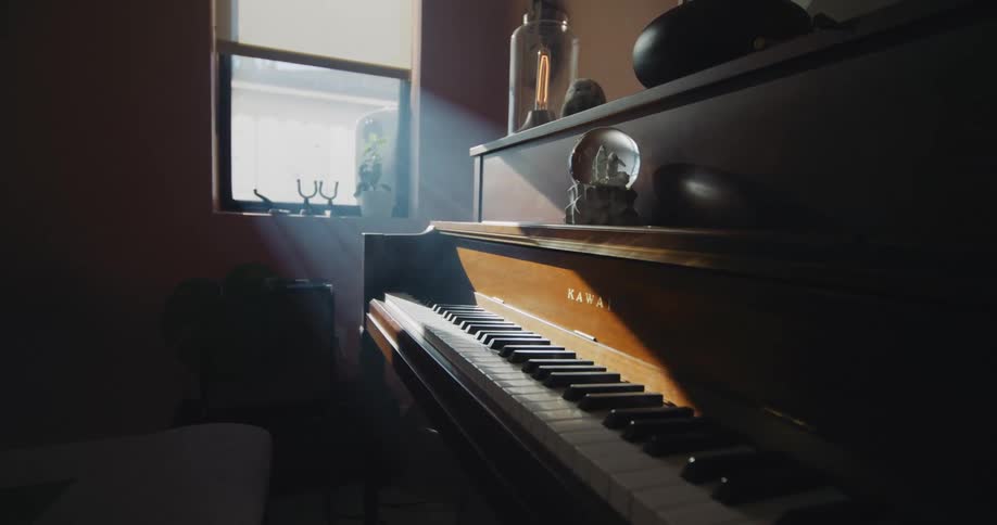 A kawai upright piano in a home near a window with sunlight shining on the keys