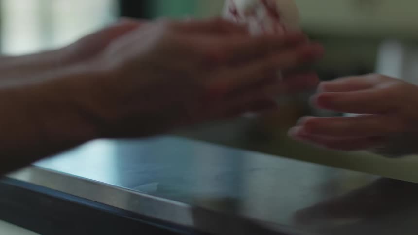 Counter helper hands ice cream to customer over metal counter