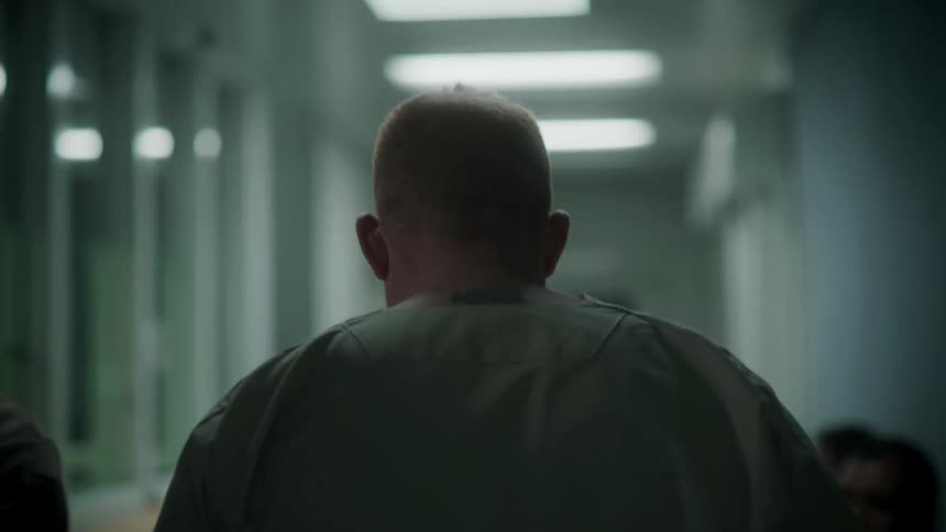 A prisoner is lead down the hallway