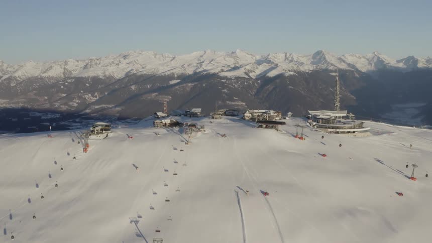 Buildings and ski lifts are at the top of a snowy mountain