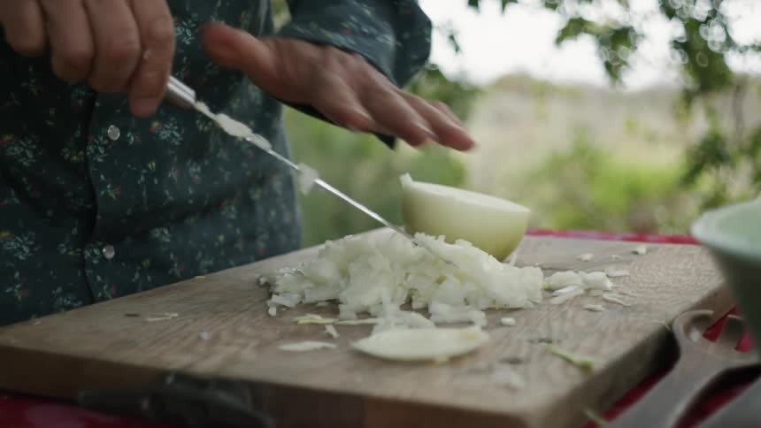 A man is cutting an onion while standing outdoors in spring