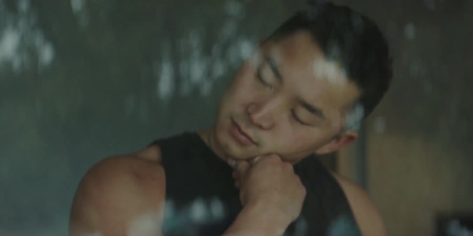 Muscular man with black shirt and white wristwatch warms up in room behind the windows
