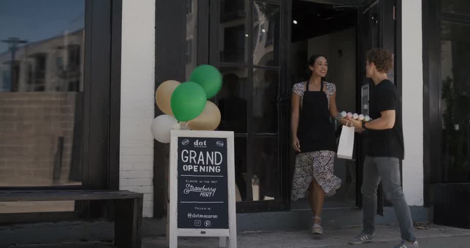 A baker follows a customer out of the store talking and waving goodbye