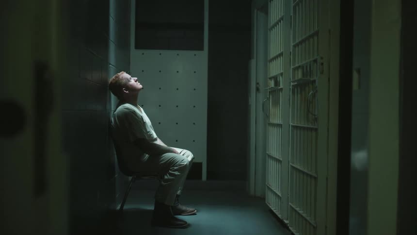 A prisoner of a jail is sitting on a chair