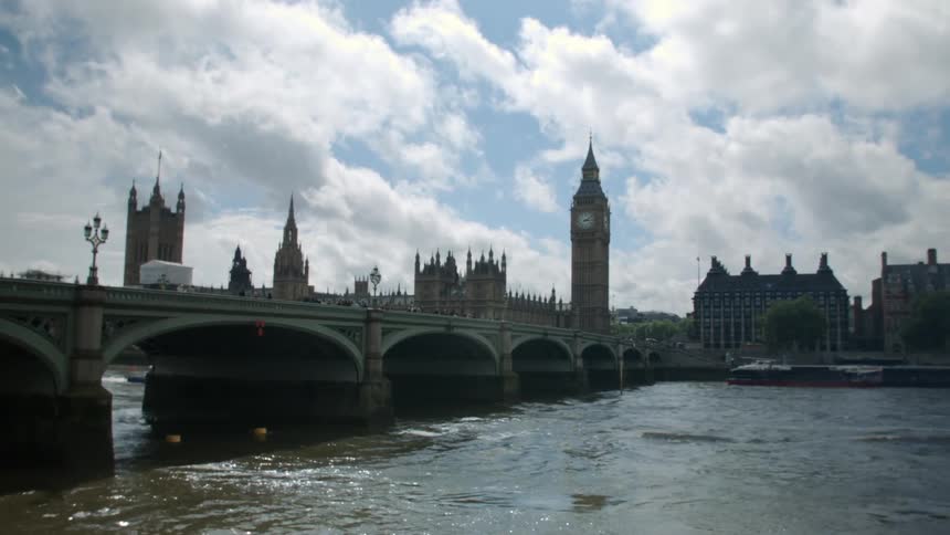 The thames river, a bridge and big ben beneath white fluffy clouds