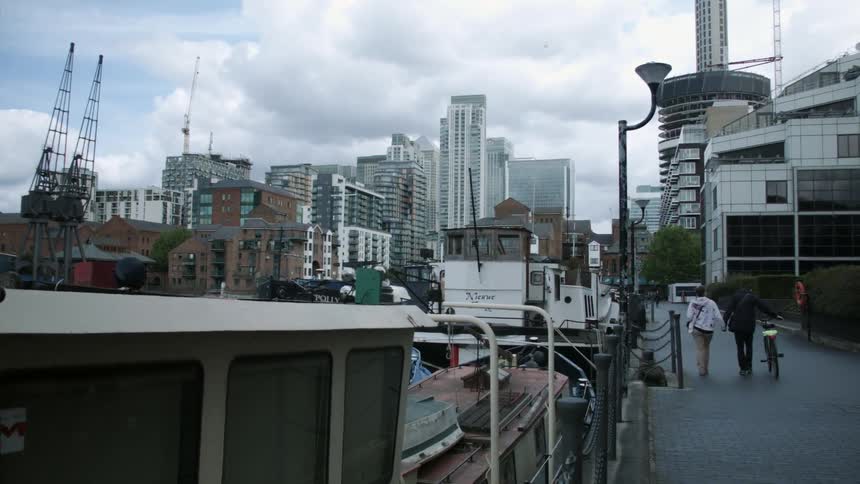 People walk down a sidewalk near a dock