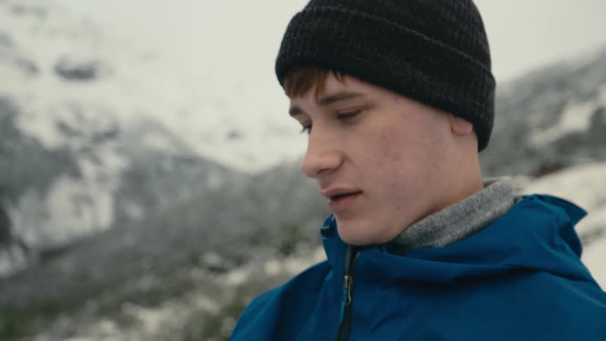 A male is standing outdoors in the wilderness during winter