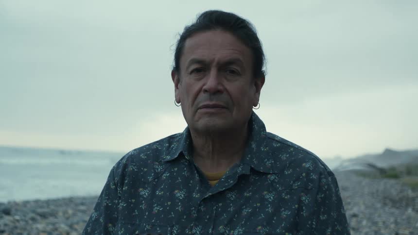 Man on beach stands with his eye closed then opens them to stare