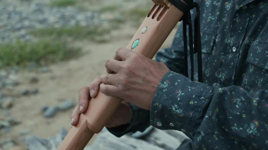A man is playing an indigenous flute