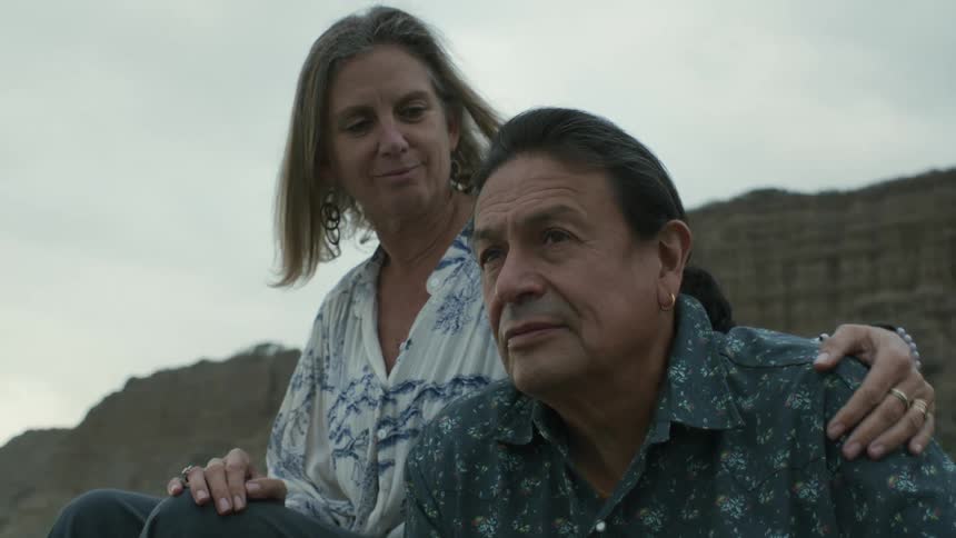 Husband and wife are sitting at the beach together