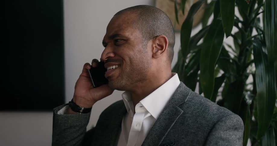 A man smiles as he talks on a smart phone in an office
