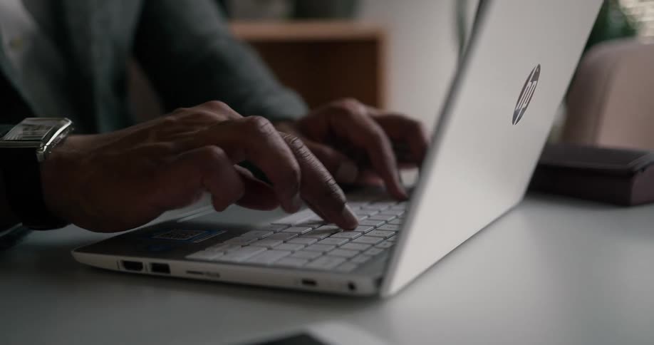 Professional man sitting at the desk in an office space typing on his laptop