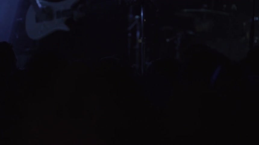 A crowd and a band bathed in blue lights