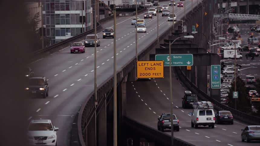 Cars travel in both directions on a freeway going through an urban area