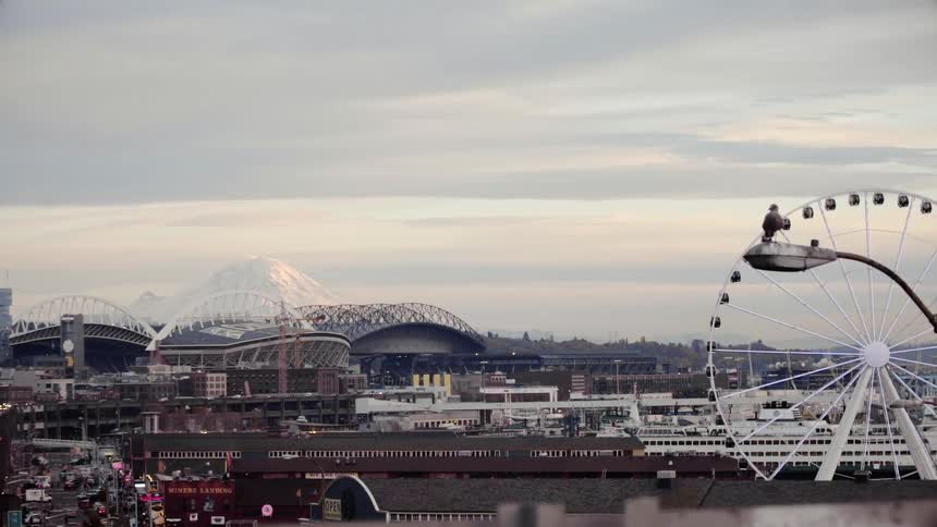 A ferris wheel rotates with city buildings in the background