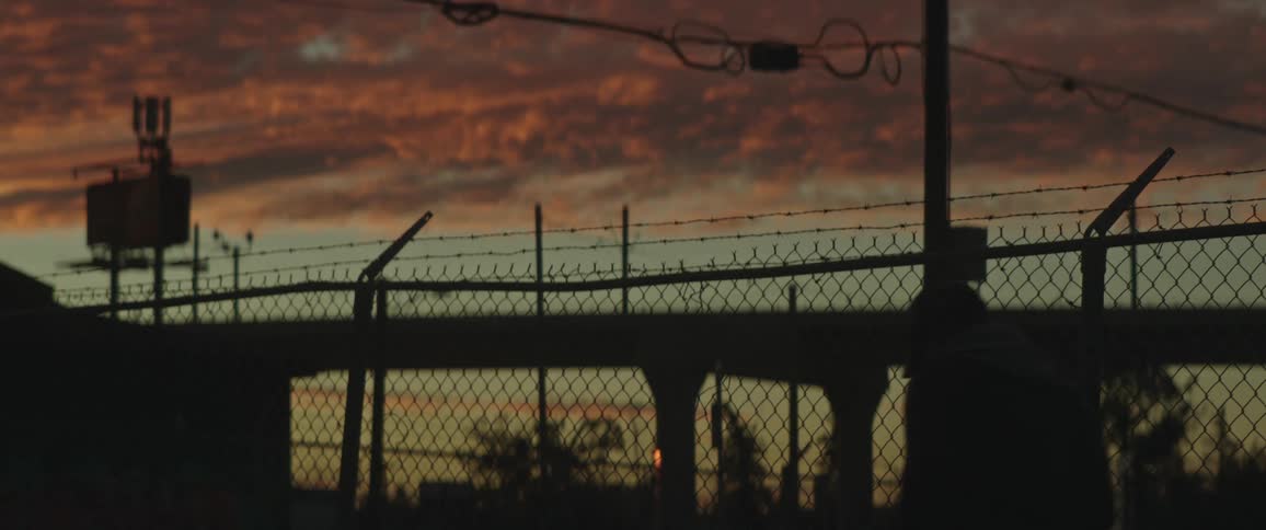 A man walks past a chain link fence along the interstate