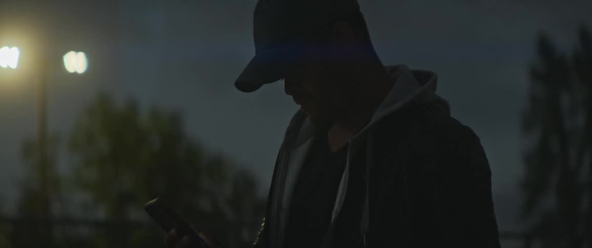 A man checks his smartphone while standing in the park