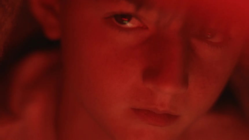 A boy looks around in the dark under a blanket tent